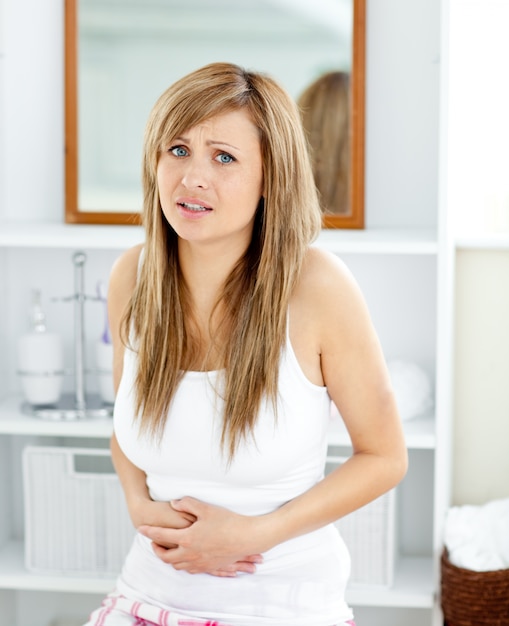 Blond woman having a stomachache in her bathroom