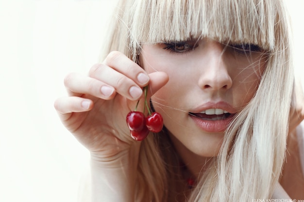 Photo blond woman holding cherries