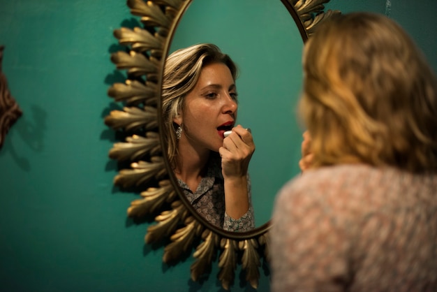 Blond woman putting on lipstick