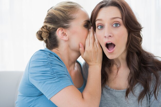 Blond woman revealing secret to her friend