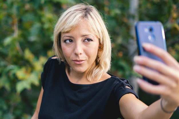 ブロンドの女性が携帯電話でセルフィーを撮っている