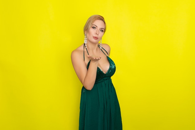 Blond woman wearing green evening dress over yellow