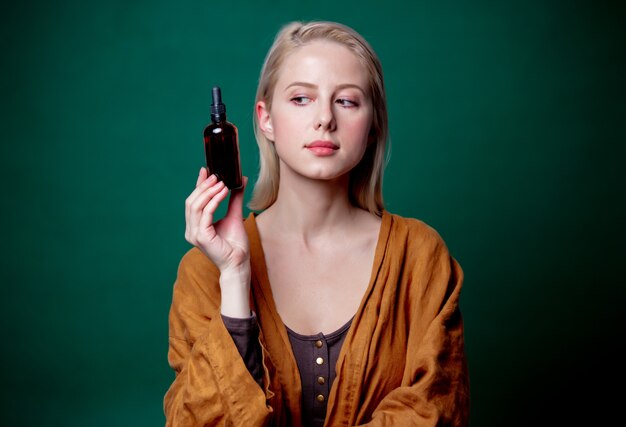 Blond woman with black bottle on green scene