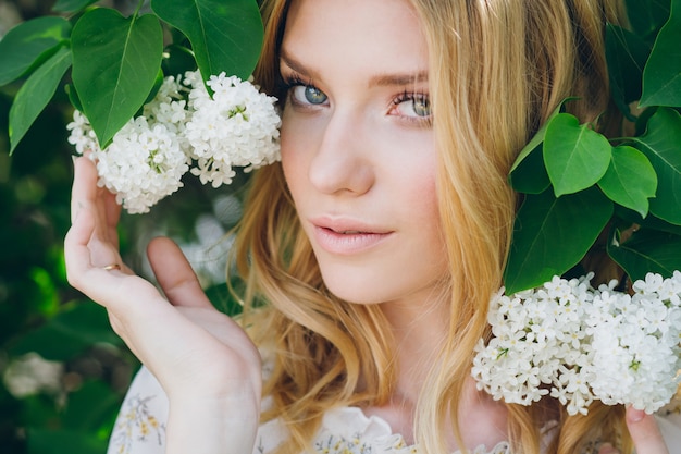 Blond woman with lilac flowers in the spring