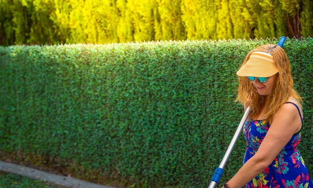 Blond woman with wet hair wearing sun visor sunglasses happy and smiling in flowery colorful dress