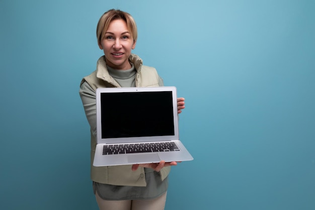 Blond young woman demonstrates a laptop screen with a mockup for advertising