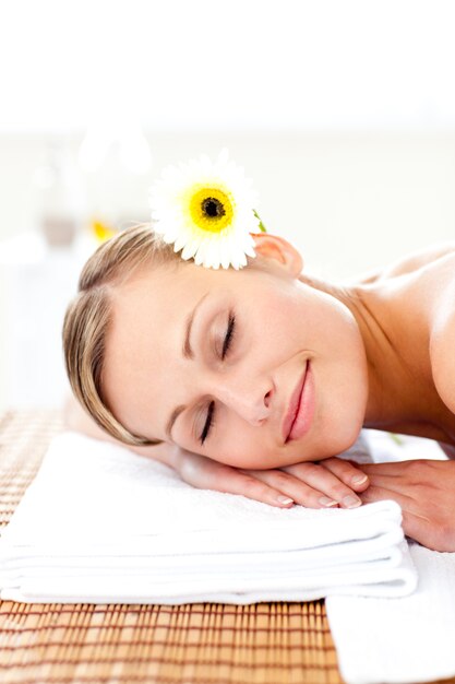 Blond young woman with flowers in her hair with closed eyes in a spa center