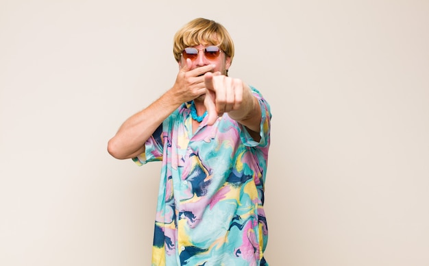 Blonde adult caucasic man laughing at you, pointing at front and making fun of or mocking you