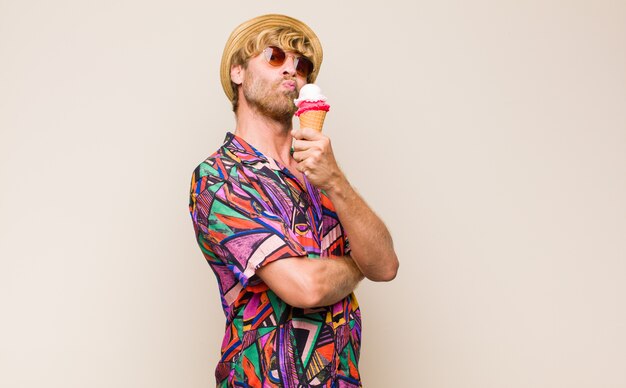 Blonde adult man holding an ice cream with a hat and sun glasses