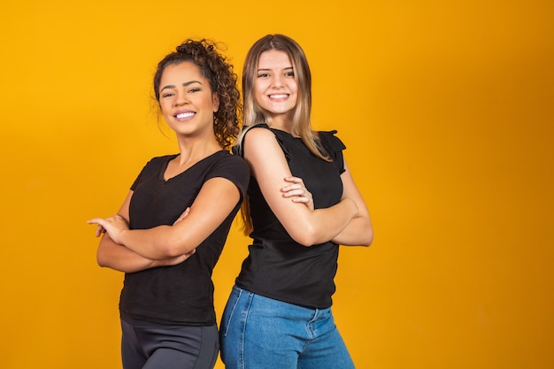 Blonde and afro girlfriends on yellow background. a white blonde woman and an afro brunette, diversity concept