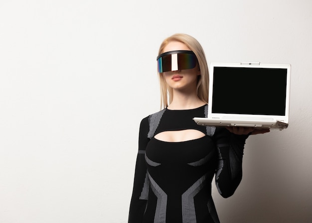Femmina bionda androide in occhiali vr e laptop su sfondo bianco.