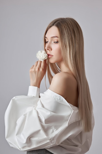 Blonde beauty woman holds white flower in hand. Beautiful soft hands and soft skin. Cosmetics for beauty hand care