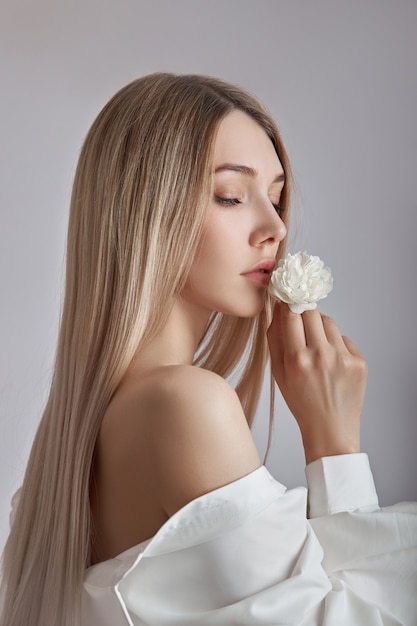 Blonde beauty woman holds white flower in hand.