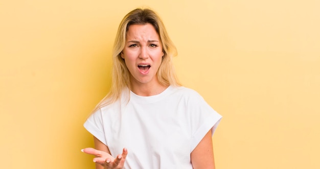 Blonde blanke vrouw kijkt boos geïrriteerd en gefrustreerd schreeuwend wtf of wat is er mis met je?