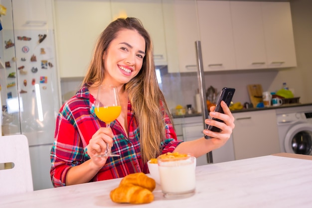 Blonde blanke vrouw met een vers sinaasappelsap voor het ontbijt in haar keuken