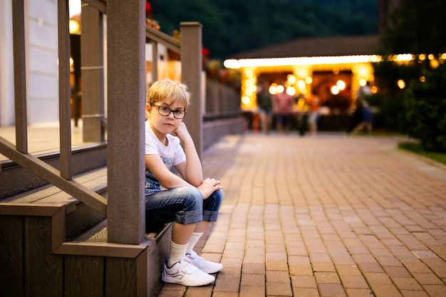 Blonde boy in the big glasses walking outside in the evening