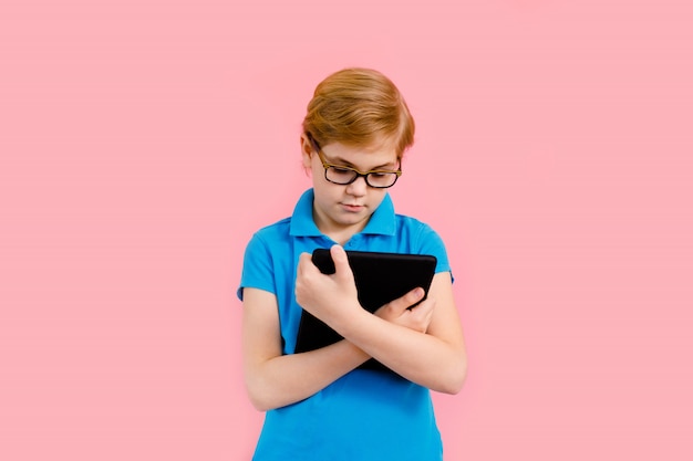 Photo blonde boy in t-shirt holding a tablet