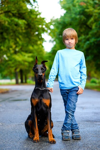 Blonde boy with doberman in summer park