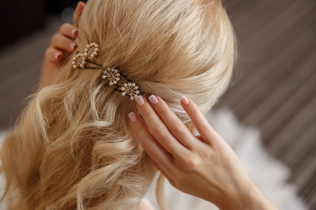 Blonde bride adjusts her hairstyle at wedding day