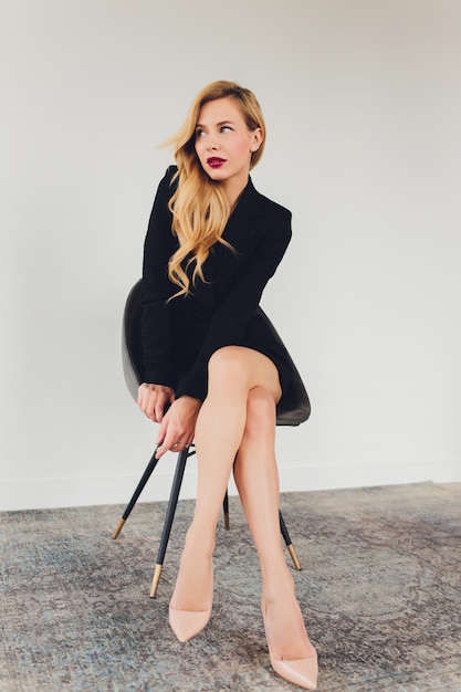 Blonde businesswoman in a black suit on a chair