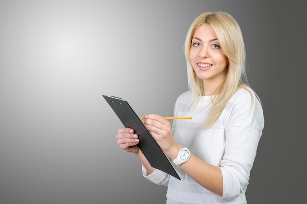 Blonde businesswoman writing notes in the clipboard