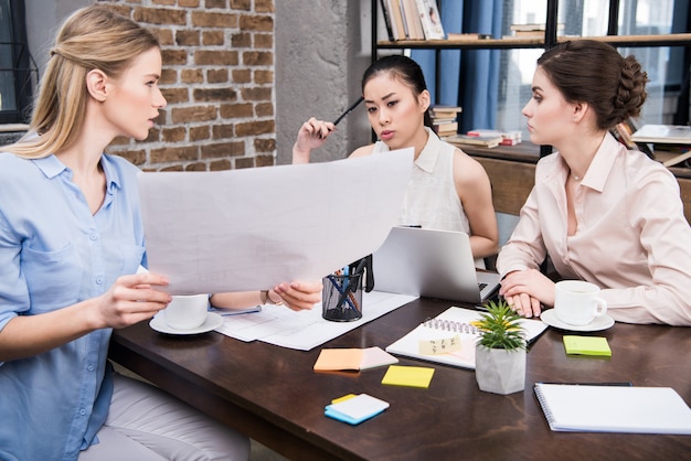 Blonde businesswomen presenting business project to her multicultural colleagues modern office