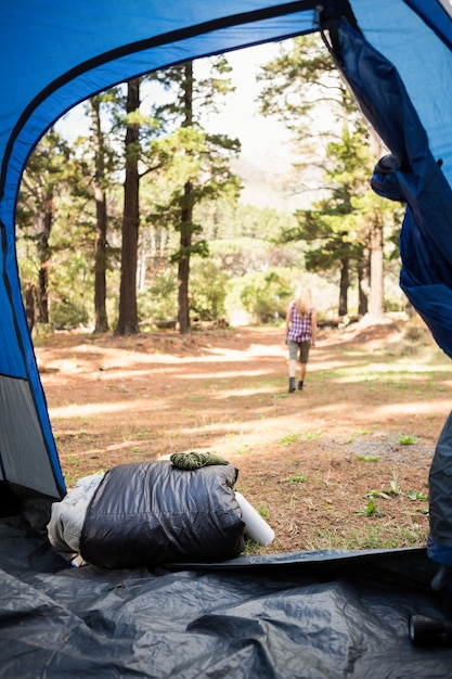 Blonde camper walking away from tent