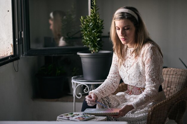 Foto donna bionda caucasica matura con un vestito bianco di pizzo e una fascia nei capelli, pittura calma e rilassata.