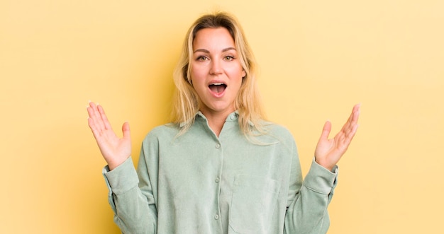 Blonde caucasian woman feeling happy excited surprised or shocked smiling and astonished at something unbelievable