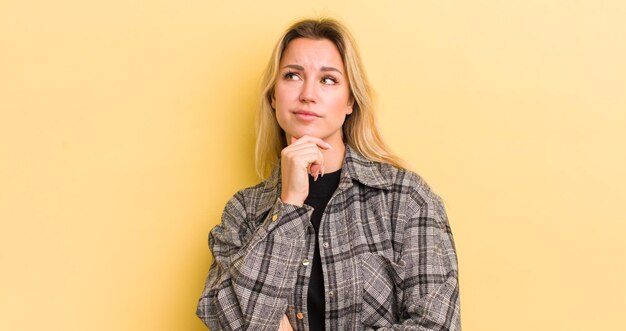 Blonde caucasian woman thinking feeling doubtful and confused with different options wondering which decision to make