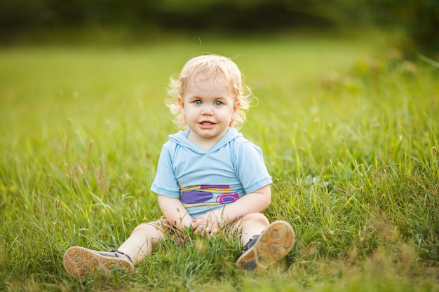 Blonde curly baby boy playing in the summer park