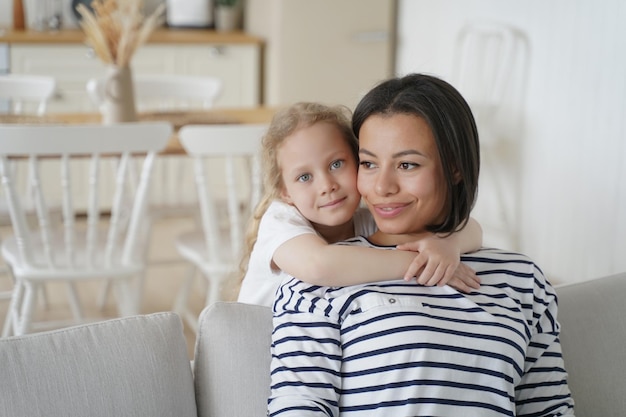 Blonde cute little girl hugs mom Young spanish mother and european kid Child adoption concept