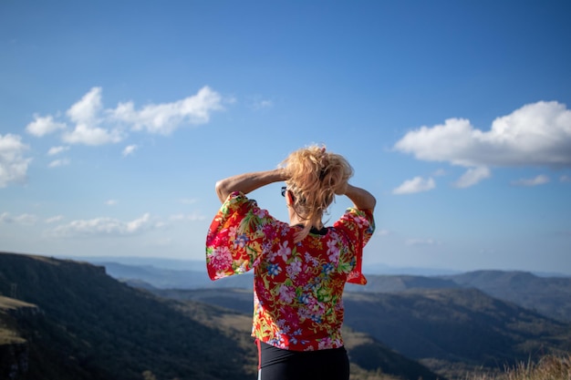 blonde dame met blouse met print en zonnebril die haar haar rug aan rug houdt