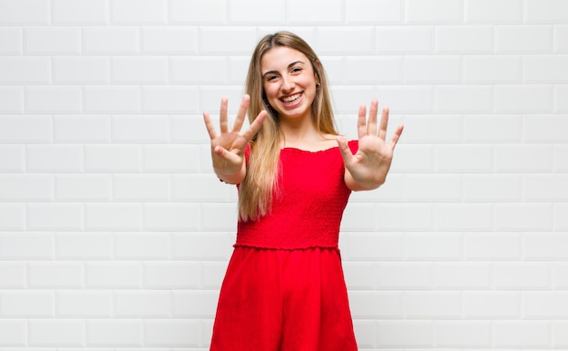 Blonde en vrouw die vriendelijk glimlacht kijkt, nummer negen of negende met vooruit hand toont, aftellend