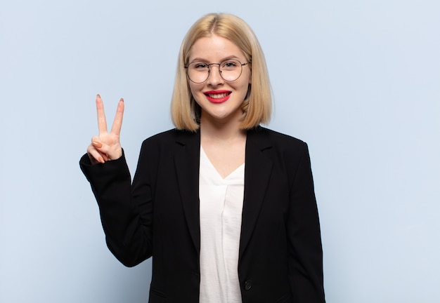 Blonde en vrouw die vriendelijk glimlacht kijkt, nummer twee of seconde met vooruit hand toont, aftellend