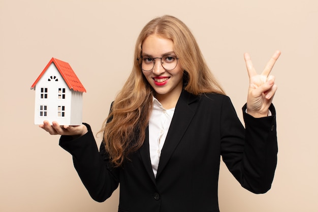 Blonde en vrouw die vriendelijk glimlacht kijkt, nummer twee of seconde met vooruit hand toont, aftellend