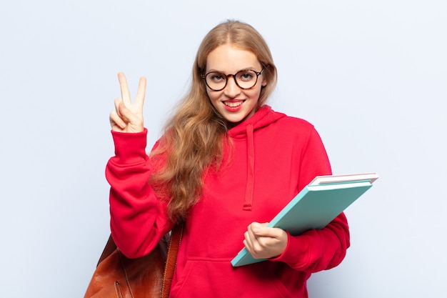 Blonde en vrouw die vriendelijk glimlacht kijkt, nummer twee of seconde met vooruit hand toont, aftellend