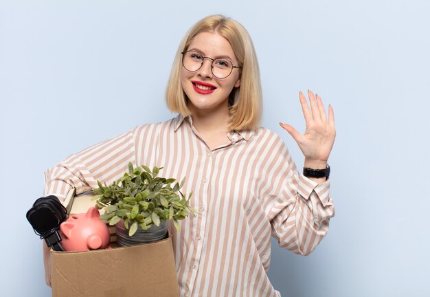 Blonde en vrouw die vriendelijk glimlacht kijkt, nummer vijf of vijfde met vooruit hand toont, aftellend