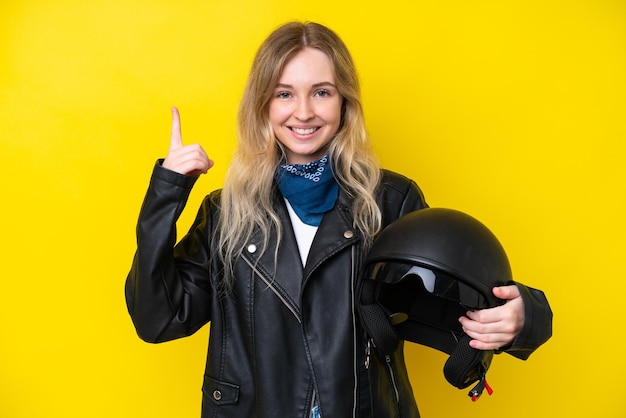 Blonde english young girl with a motorcycle helmet isolated on yellow background pointing up a great idea