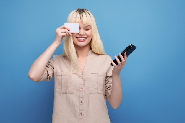 Foto blonde europese jonge vrouw met creditcard en smartphone