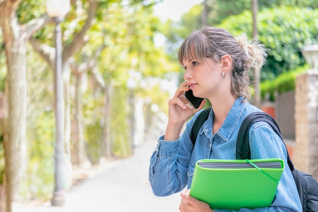 写真 ブロンドの女性学生が携帯電話で聞いている