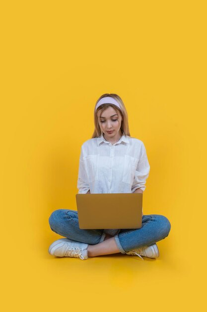 Blonde focused university student sit floor legs crossed holding modern laptop pc computer