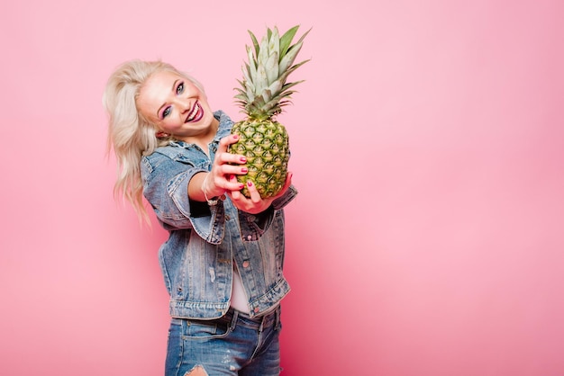 Blonde gelukkige vrouw met ananas die zich voordeed op kleur background