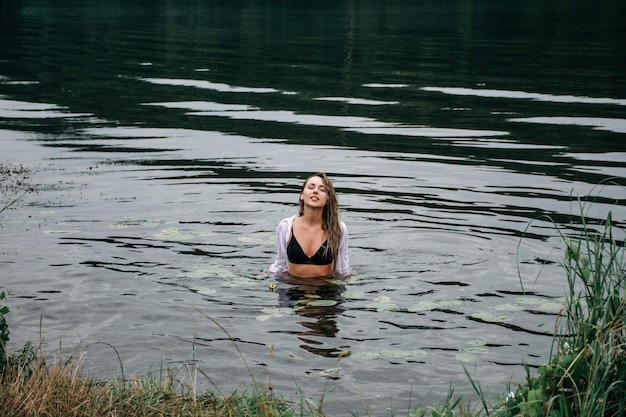 Blonde gelukkige vrouw zwemmen in de rivier tussen de golven.