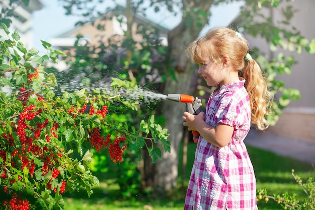 a blonde girl baby walks on a sunny day takes care of the garden