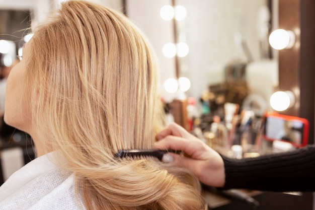 Ragazza bionda in un salone di bellezza che fa un'acconciatura. avvicinamento.