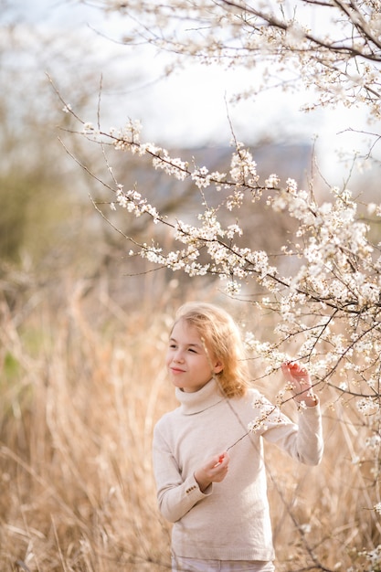 Ragazza bionda nel giardino fiorito.