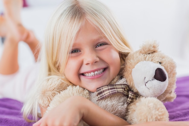 Blonde girl embracing her teddy bear