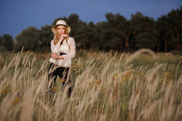 blonde girl in a hat on nature