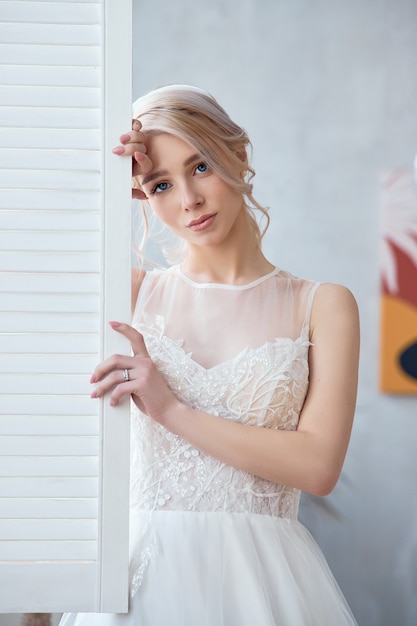 아름 다운 하얀 웨딩 드레스에 금발 소녀입니다. 여자 신부는 결혼식 전에 신랑을 기다리고 있습니다